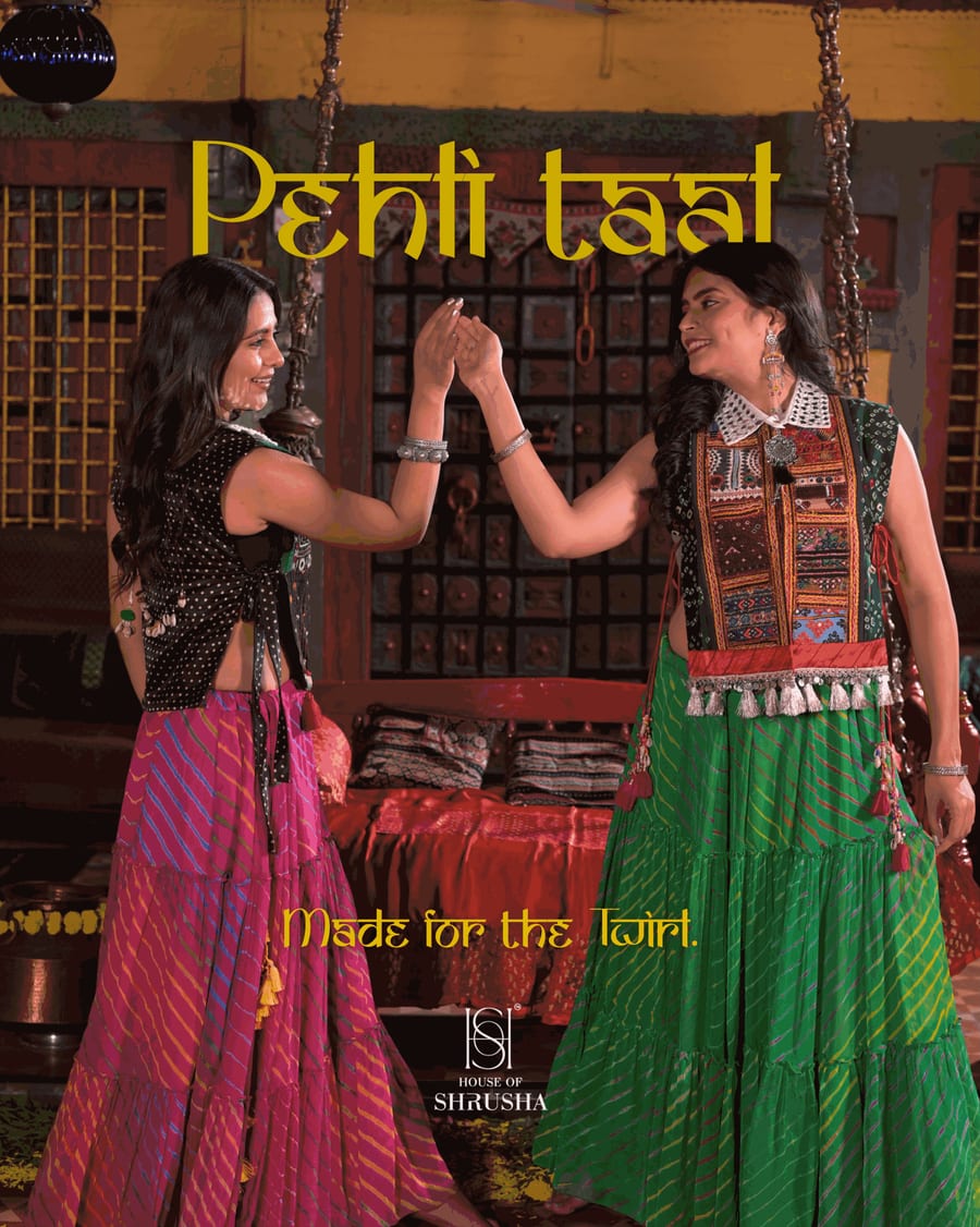 Two women in embroidered bibs and tiered lehariya skirts face each other mid-dance with raised hands in an old-style house interior. The headline reads Pehli taal, Made for the twirl, with the House of Shrusha logo.